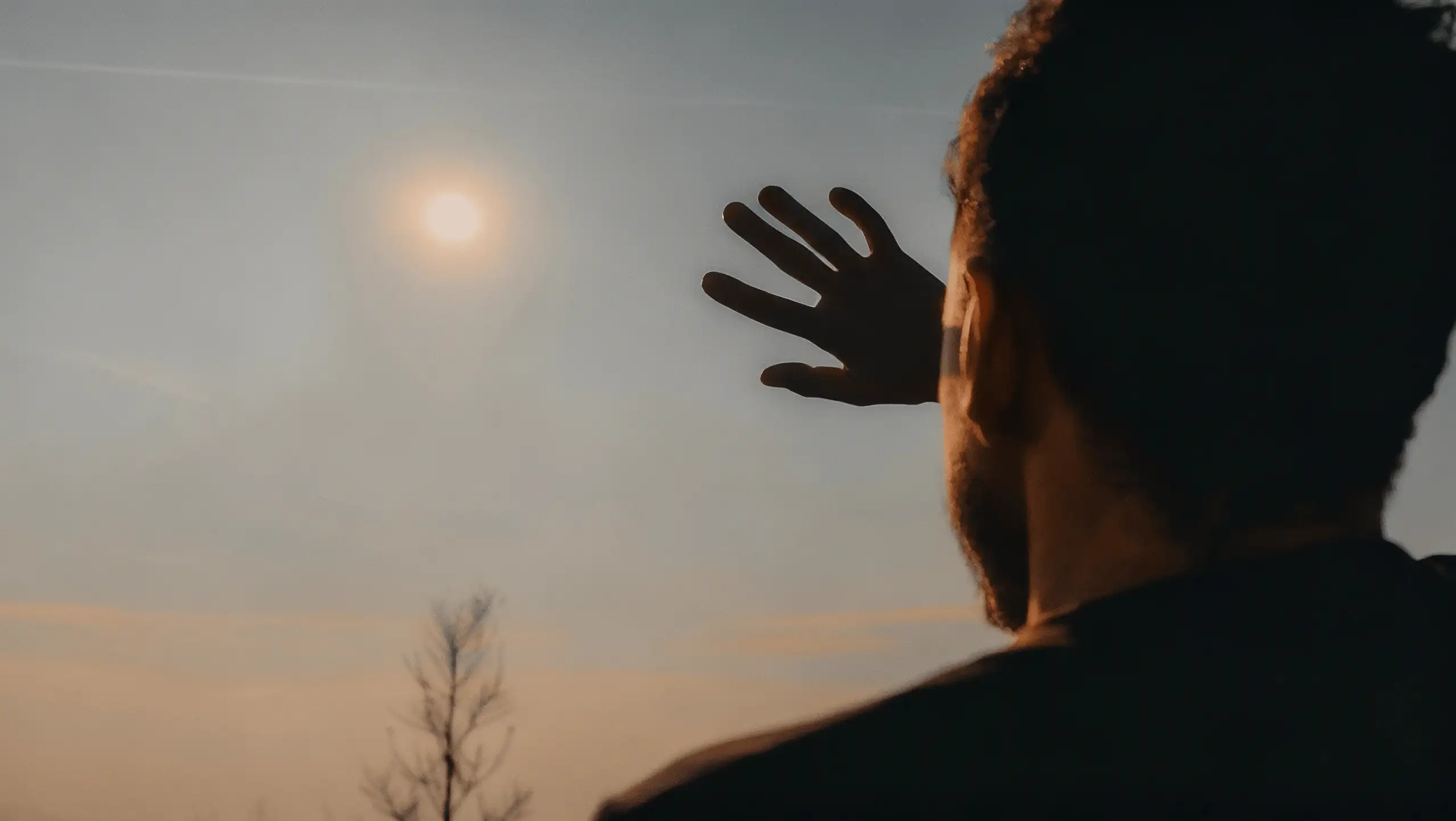 Silhouette of a person shielding their eyes from the sun